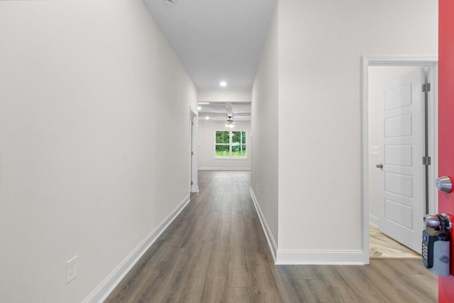 corridor featuring baseboards and wood finished floors