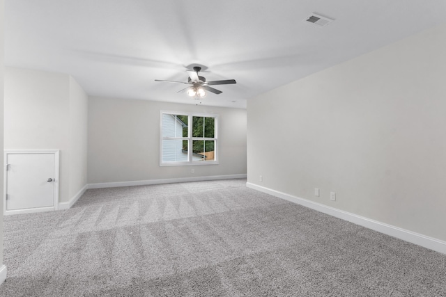 carpeted spare room with baseboards, visible vents, and ceiling fan