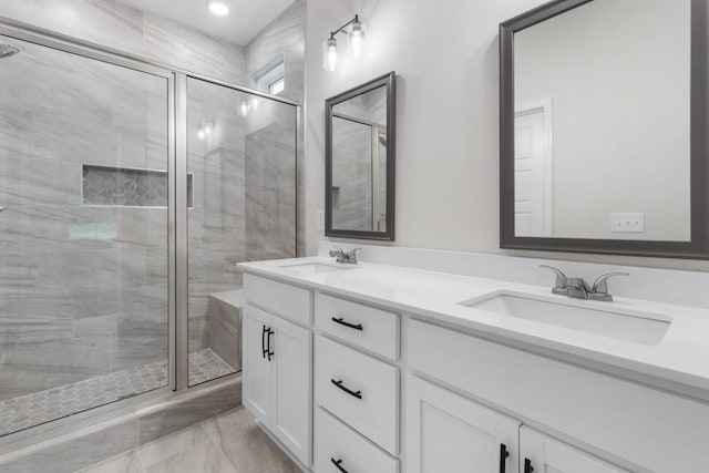 bathroom with double vanity, a shower stall, and a sink