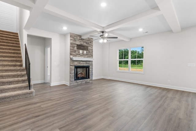 unfurnished living room featuring beamed ceiling, a ceiling fan, wood finished floors, stairway, and baseboards