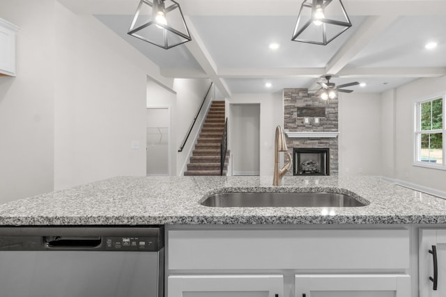 kitchen featuring beamed ceiling, dishwasher, a fireplace, and a sink