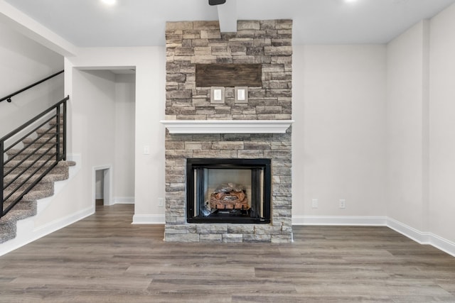 unfurnished living room with wood finished floors, a fireplace, and baseboards