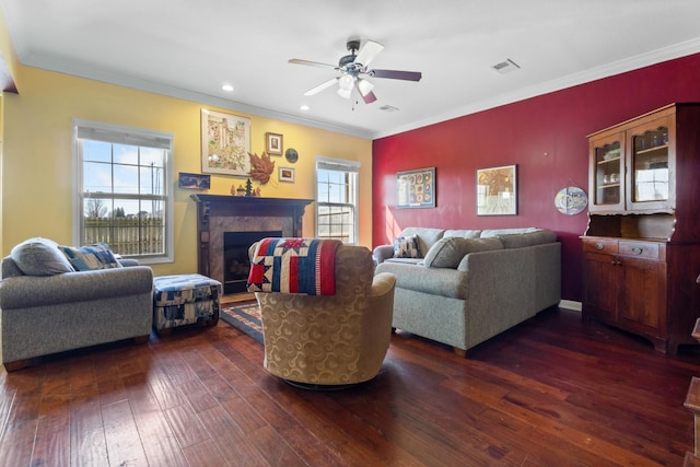 living area featuring dark wood finished floors, visible vents, a fireplace, and crown molding