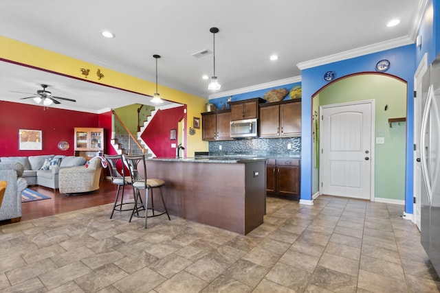 kitchen with a kitchen bar, visible vents, stainless steel appliances, decorative backsplash, and hanging light fixtures