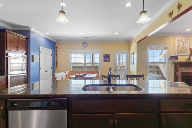 kitchen with a sink, stainless steel appliances, a wealth of natural light, and dark stone countertops