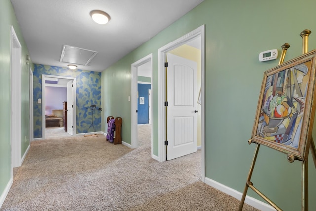 hallway featuring attic access, baseboards, and carpet