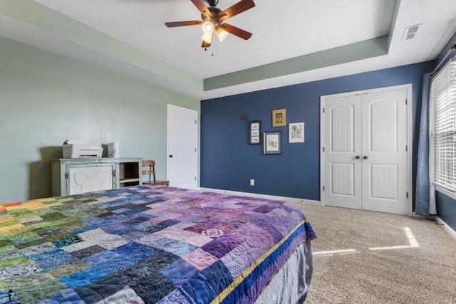 bedroom with visible vents, baseboards, carpet flooring, a raised ceiling, and a ceiling fan