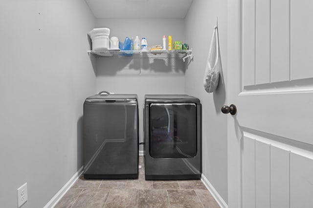 washroom featuring laundry area, baseboards, and separate washer and dryer