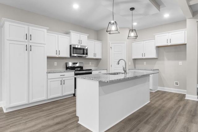 kitchen featuring a center island with sink, appliances with stainless steel finishes, wood finished floors, white cabinets, and a sink