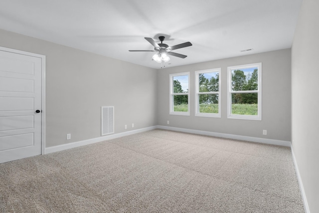 carpeted empty room with visible vents, baseboards, and a ceiling fan