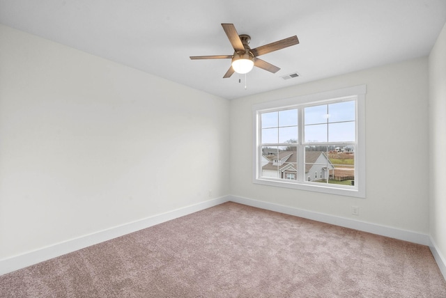 carpeted spare room with a ceiling fan, baseboards, and visible vents