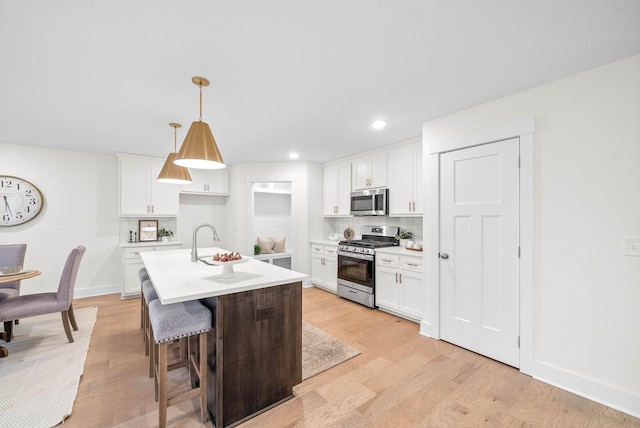 kitchen with light wood-style flooring, backsplash, stainless steel appliances, white cabinets, and light countertops