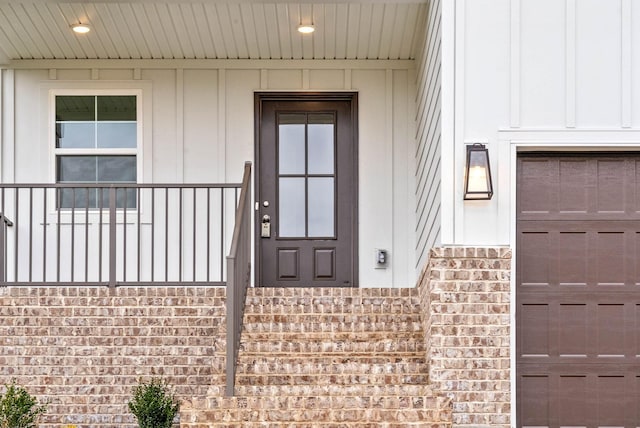 entrance to property featuring a garage and brick siding