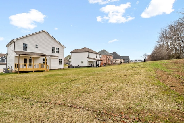 back of property with a deck, a yard, a ceiling fan, and central AC