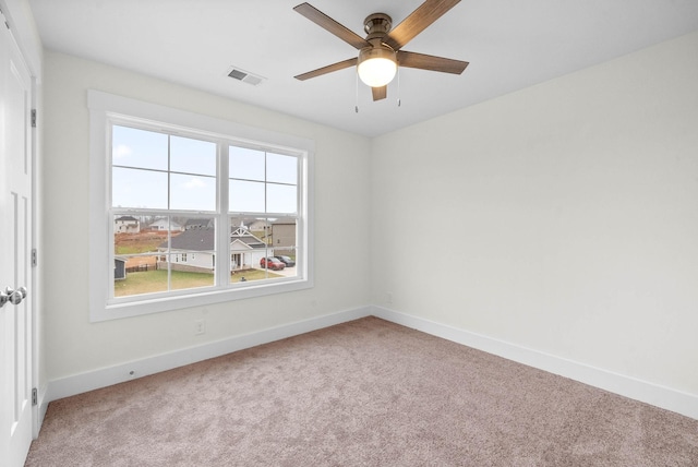 carpeted empty room featuring visible vents, ceiling fan, and baseboards