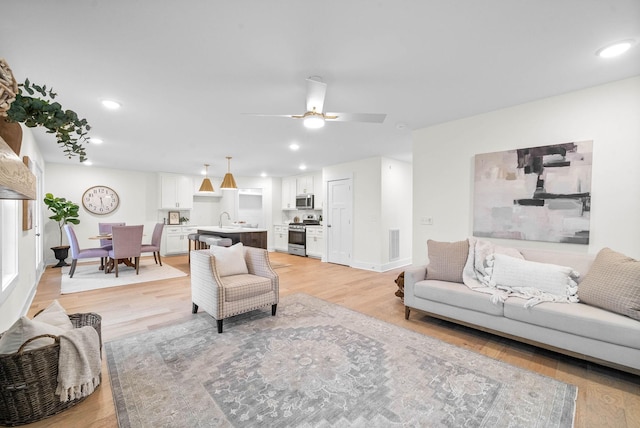 living area with light wood finished floors, visible vents, recessed lighting, and ceiling fan