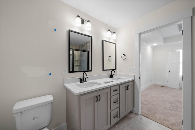 full bath featuring a sink, baseboards, toilet, and double vanity