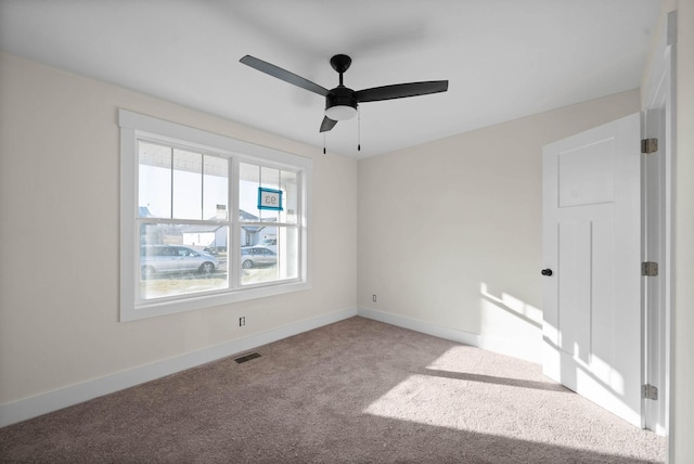 carpeted empty room featuring visible vents, a ceiling fan, and baseboards