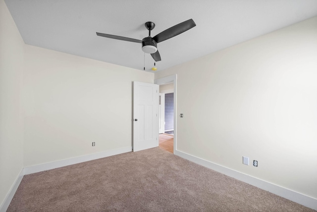 carpeted empty room featuring ceiling fan and baseboards