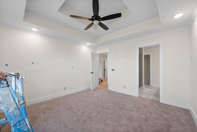 unfurnished bedroom with a tray ceiling, light colored carpet, baseboards, and ornamental molding