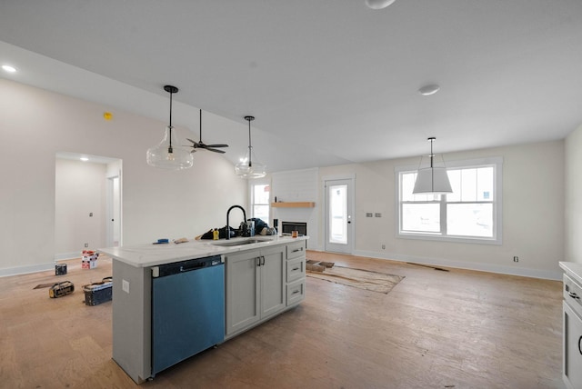 kitchen featuring light wood-style flooring, a sink, open floor plan, dishwashing machine, and hanging light fixtures