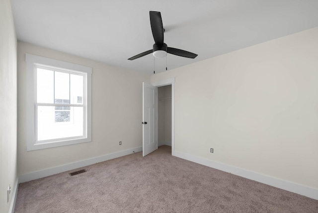 unfurnished bedroom with baseboards, visible vents, ceiling fan, a closet, and light carpet