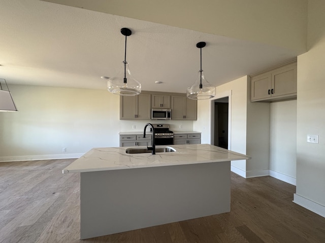 kitchen featuring a sink, light stone countertops, appliances with stainless steel finishes, and gray cabinetry