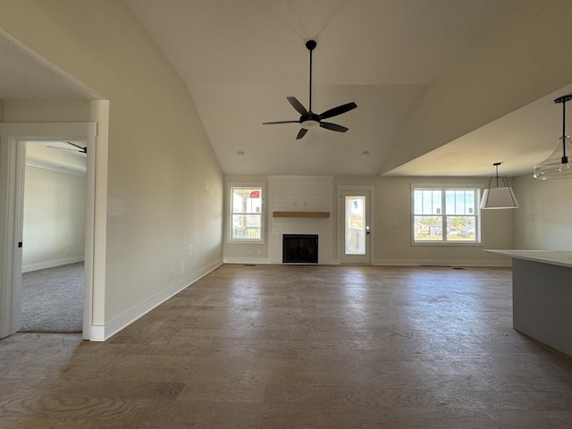 unfurnished living room with high vaulted ceiling, a ceiling fan, wood finished floors, a fireplace, and baseboards