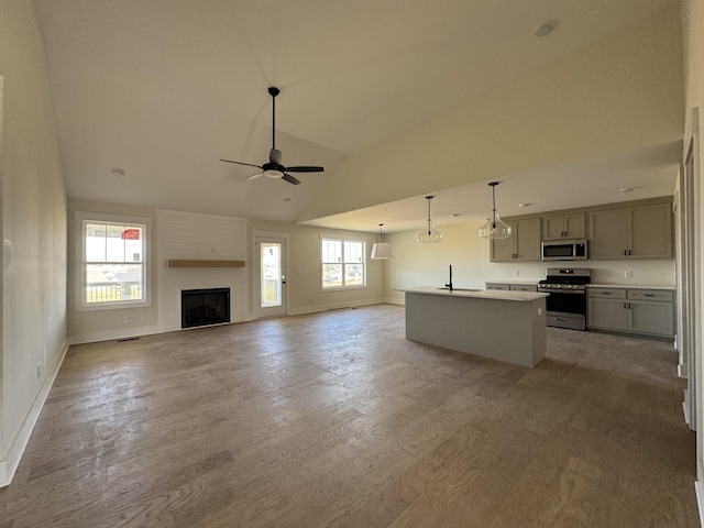 unfurnished living room featuring lofted ceiling, light wood-style floors, baseboards, and ceiling fan