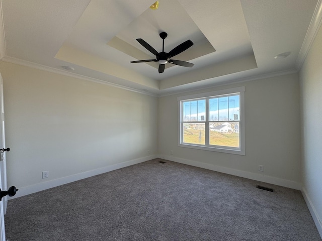 carpeted spare room featuring visible vents, a raised ceiling, baseboards, and ornamental molding