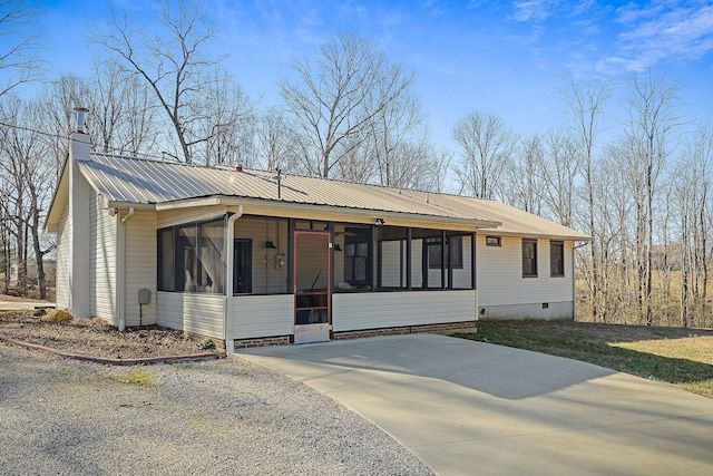 view of front of house with a front lawn, metal roof, a sunroom, and a chimney