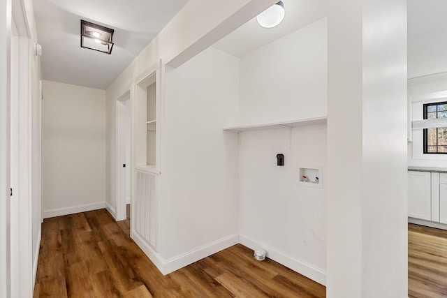 clothes washing area with baseboards, wood finished floors, hookup for a washing machine, and laundry area