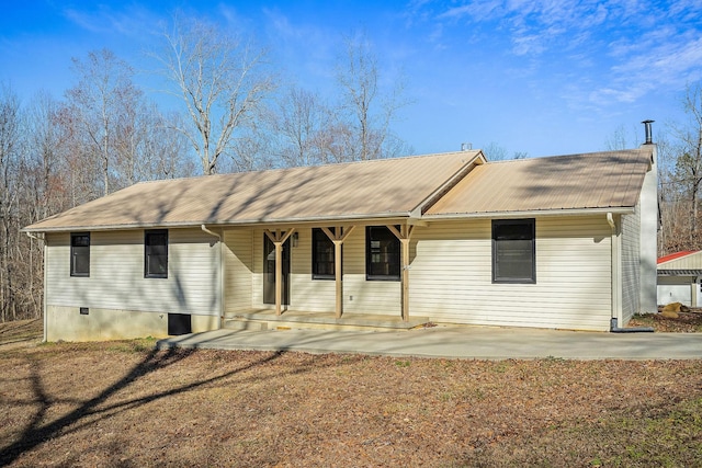 ranch-style house featuring a chimney, covered porch, and metal roof