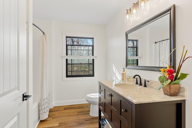 full bathroom with plenty of natural light, toilet, wood finished floors, and vanity