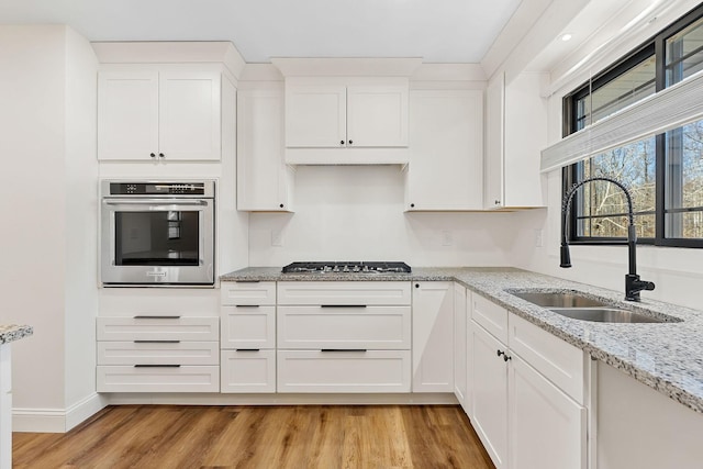 kitchen featuring a sink, light wood-type flooring, white cabinetry, and stainless steel appliances