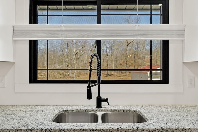 details featuring white cabinets, light stone counters, and a sink