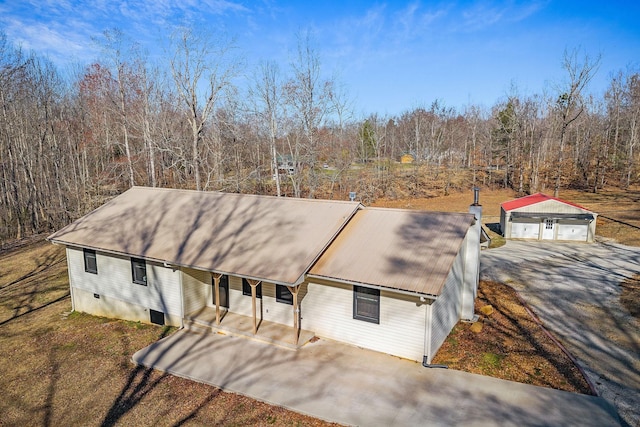 view of front of house featuring a view of trees, an outdoor structure, crawl space, and metal roof