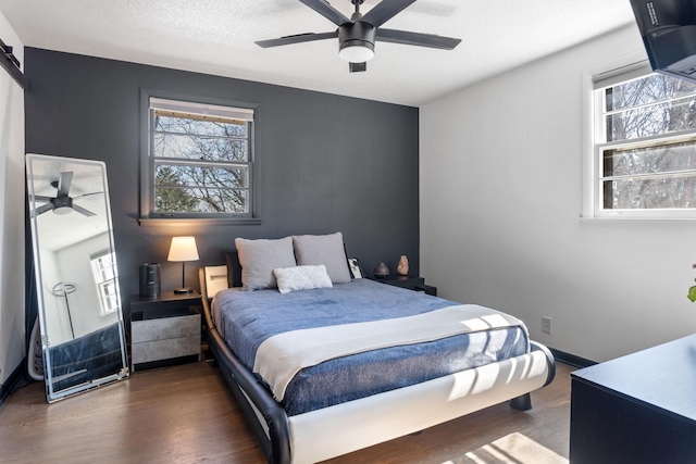 bedroom featuring multiple windows, ceiling fan, baseboards, and wood finished floors