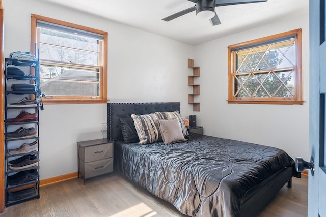 bedroom featuring baseboards, wood finished floors, and a ceiling fan