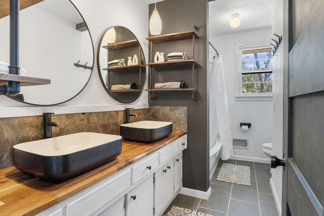 bathroom featuring tile patterned floors, visible vents, toilet, and a sink