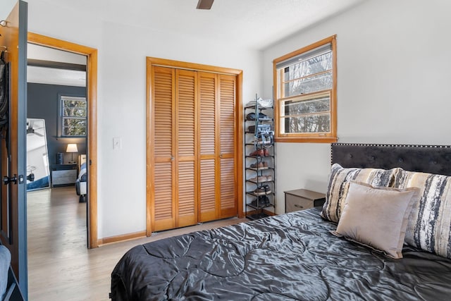 bedroom featuring ceiling fan, wood finished floors, a closet, and baseboards