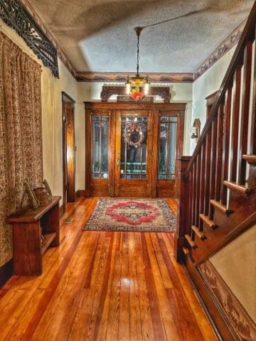 entryway with stairway, wood-type flooring, and a textured ceiling