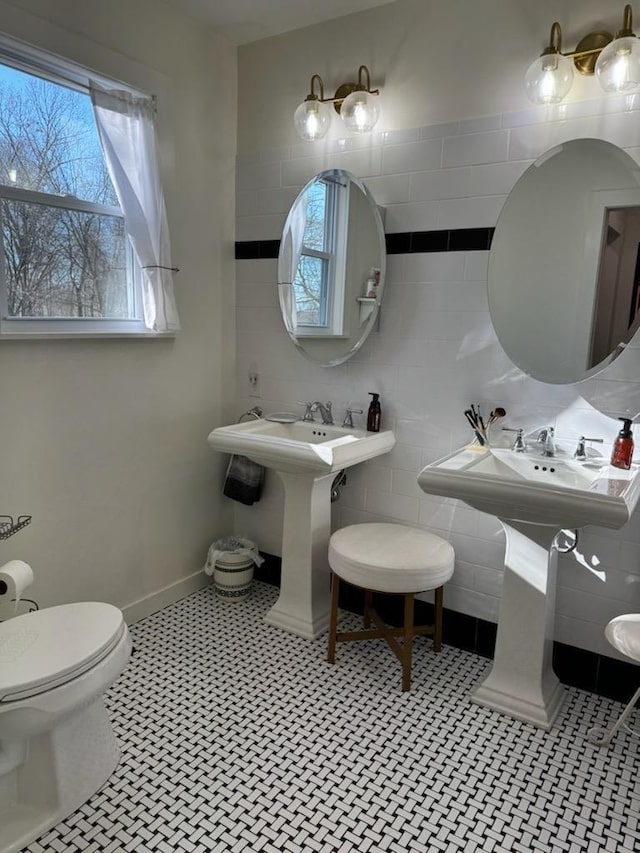 half bathroom featuring a wealth of natural light, baseboards, toilet, and tile walls