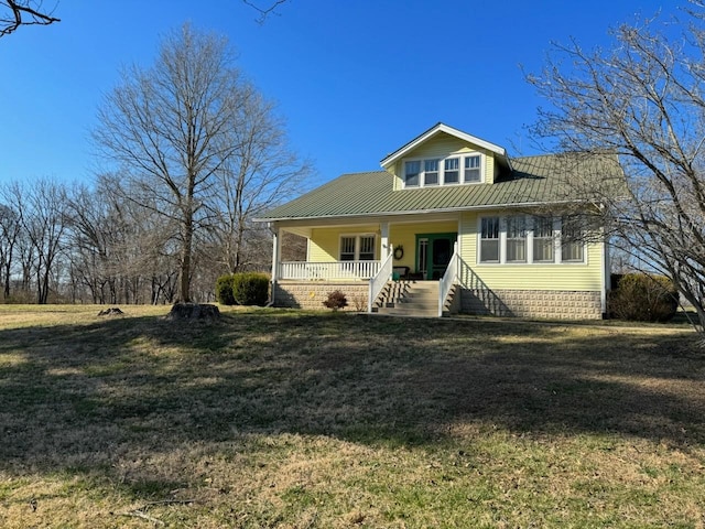 view of front of house featuring covered porch, metal roof, and a front yard