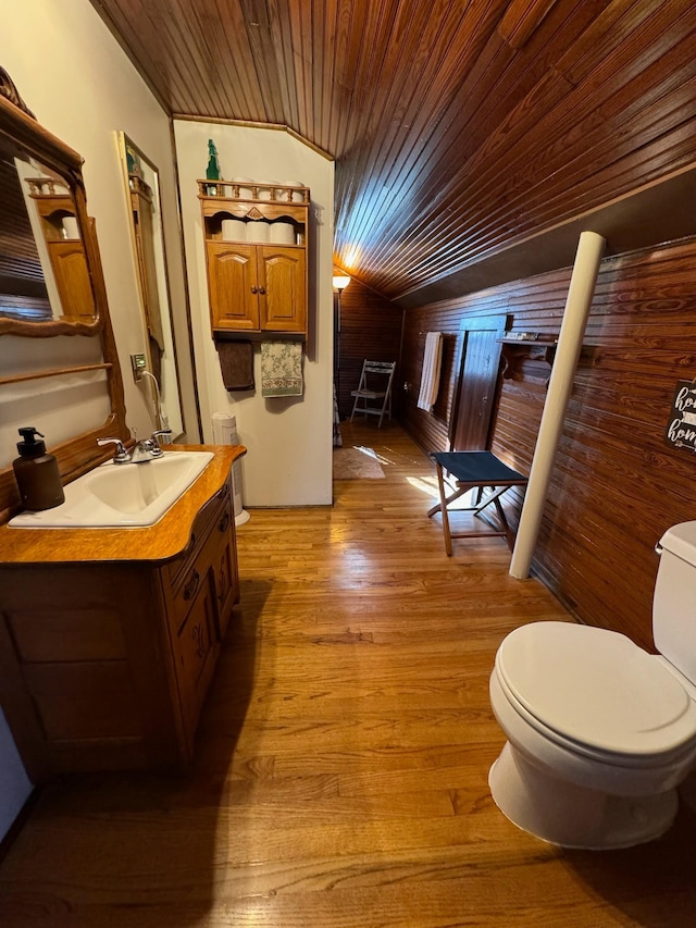 half bathroom featuring toilet, lofted ceiling, wooden ceiling, wood finished floors, and vanity