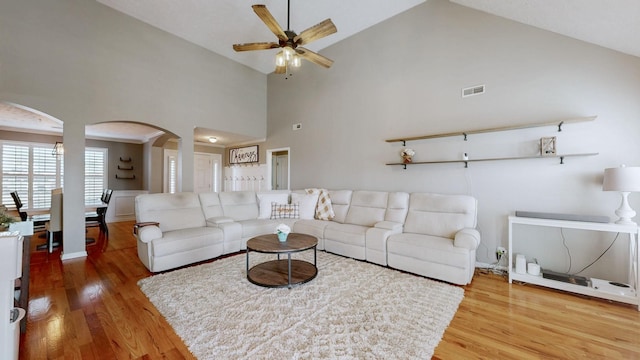 living room with visible vents, high vaulted ceiling, wood finished floors, arched walkways, and ceiling fan