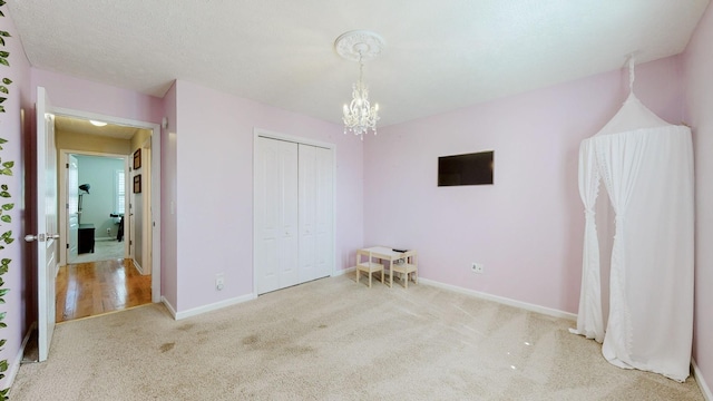 unfurnished bedroom with an inviting chandelier, a closet, baseboards, and carpet floors