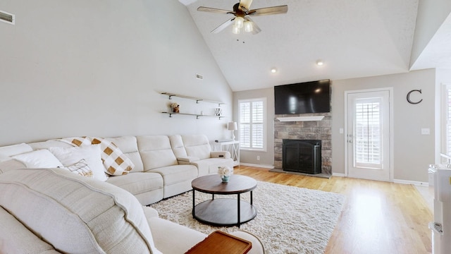 living room featuring baseboards, a fireplace, light wood-style floors, high vaulted ceiling, and a ceiling fan