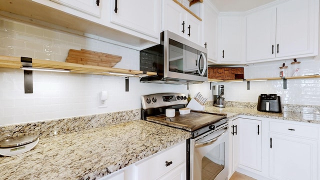 kitchen with open shelves, light stone counters, stainless steel appliances, white cabinets, and decorative backsplash