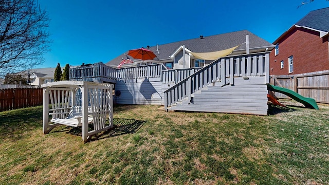 back of property with a yard, stairway, a wooden deck, and a fenced backyard